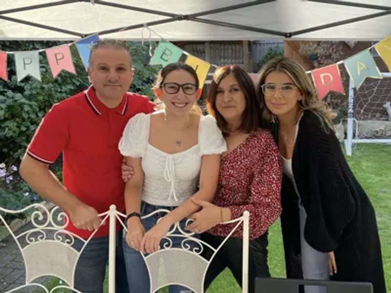 Family photo of Evie and her mum, dad and sister at a birthday party in a garden.
