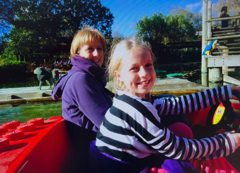 Photo of Sarah as a child with her mum smiling on a sunny day at Legoland