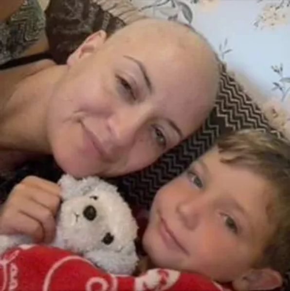 Photo of Vicki with her son. She is bald and her son is holding a cuddly toy.