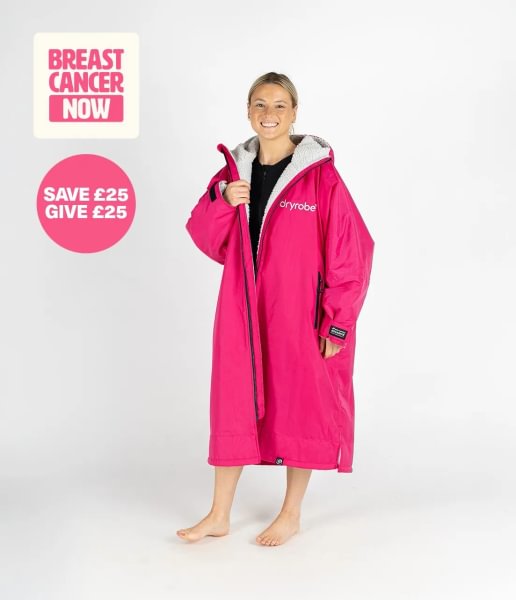 A woman is wearing a pink dryrobe. The Breast Cancer Now logo is in the corner of the image with the words 'Save £25, give £25' below it.