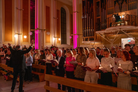 Photos of the carols concert, people singing, holding candles and enjoying the concert.
