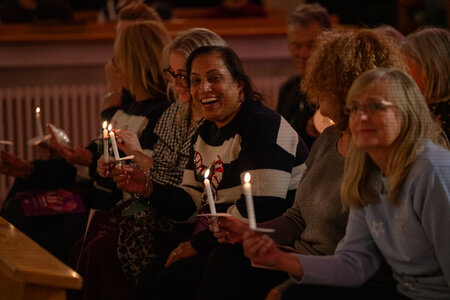 Photos of the carols concert, people singing, holding candles and enjoying the concert.