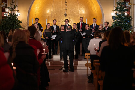 Photos of the carols concert, people singing, holding candles and enjoying the concert.