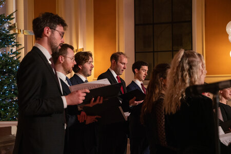 Photos of the carols concert, people singing, holding candles and enjoying the concert.