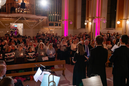 Photos of the carols concert, people singing, holding candles and enjoying the concert.