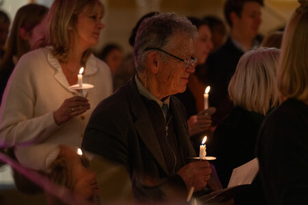 Photos of the carols concert, people singing, holding candles and enjoying the concert.