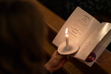 Photos of the carols concert, people singing, holding candles and enjoying the concert.