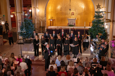 Photos of the carols concert, people singing, holding candles and enjoying the concert.