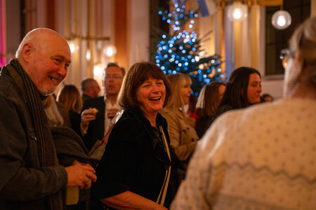 People socialising, drinking mulled wine and eating mince pies after the carols concert.