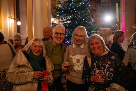 People socialising, drinking mulled wine and eating mince pies after the carols concert.