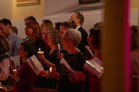 Photos of the carols concert, people singing, holding candles and enjoying the concert.