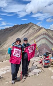 Emma and Jo standing by a mountainous ridge holding their pink Breast Cancer Now T-shirts.
