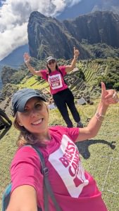 A selfie of Emma and Jo at Machu Picchu. They're holding their arms up and wearing their Breast Cancer Now t-shirts.