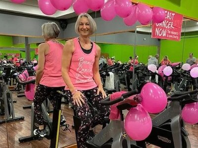 Woman wearing pink sat on a cycling machine at the gym