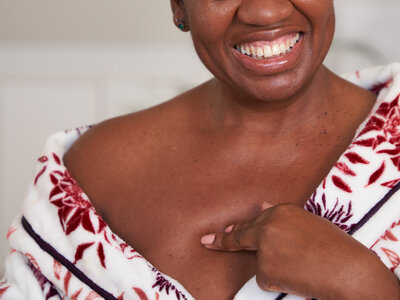 Close up photos of a woman touching her chest, wearing a floral dressing gown in her bedroom.