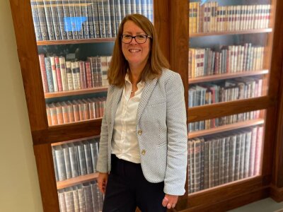 A photo of Professor Clare Foster smiling in front of a bookcase.