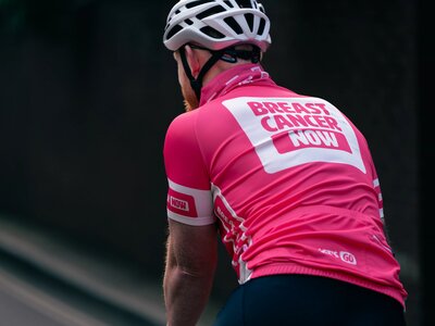 Breast Cancer Now staff wearing merchandise. Staff member Simon, wearing Breast Cancer Now cycling jersey, whilst outside on his bike.