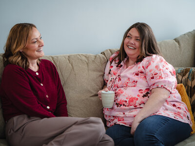 Emma and Joanne, chatting on their sofa in their home.