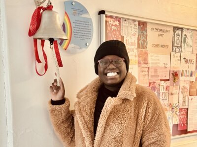 A photo of Abigail ringing a bell in a hospital to celebrate finishing treatment for breast cancer.