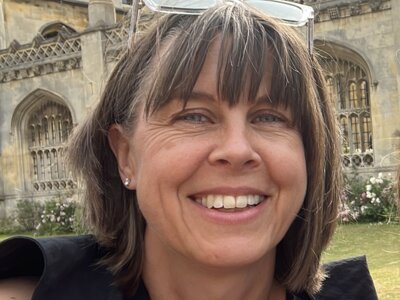 A photo of Sophie smiling standing outside the gothic stone walls of King's College Cambridge.