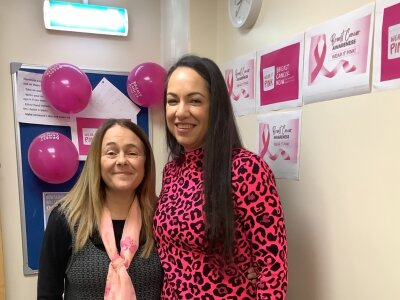 Two women wearing pink and surrounded by Breast Cancer Now posters for Wear It Pink.
