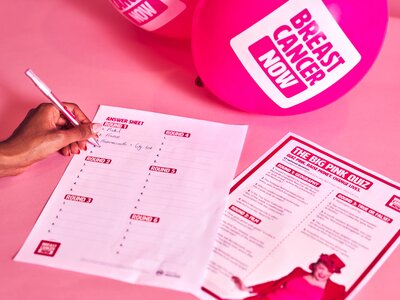 Wear it Pink fundraising materials and quiz being completed set against a light pink backdrop.