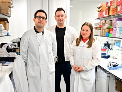 A photo of Arran Turnbull and 2 other researchers standing together in a lab.