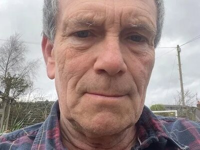 A selfie of Richard. He is standing outside and is wearing a navy and dark red shirt.