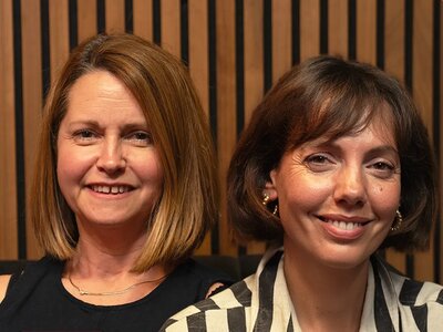 Lou, with light brown hair smiling, and Dani with dark hair and a fringe, smiling at the camera.