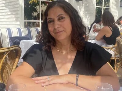 A photo of Evie's mum sitting at a table on a café terrace.