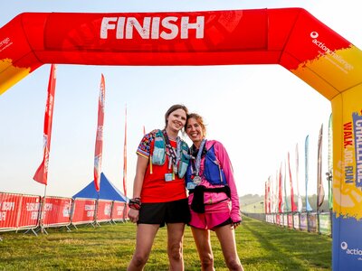 A photo of 2 women at the finish line of the North Norfolk 50 Ultra Challenge. There are both wearing medals and smiling.