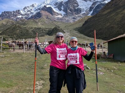 Emma and Jo wearing their pink Breast Cancer Now t-shirts with a snowy mountain in the background.