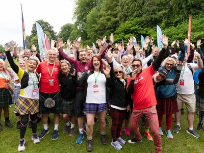 A group of participants celebrating at a Kiltwalk in Aberdeen. They are wearing kilts and tartan trousers.