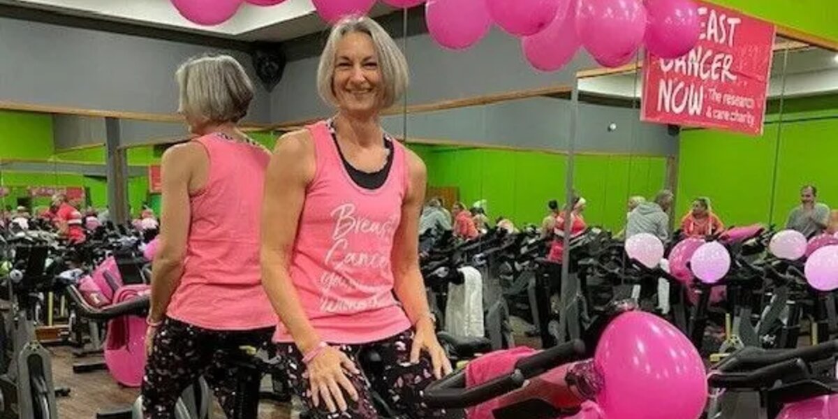 Woman wearing pink sat on a cycling machine at the gym