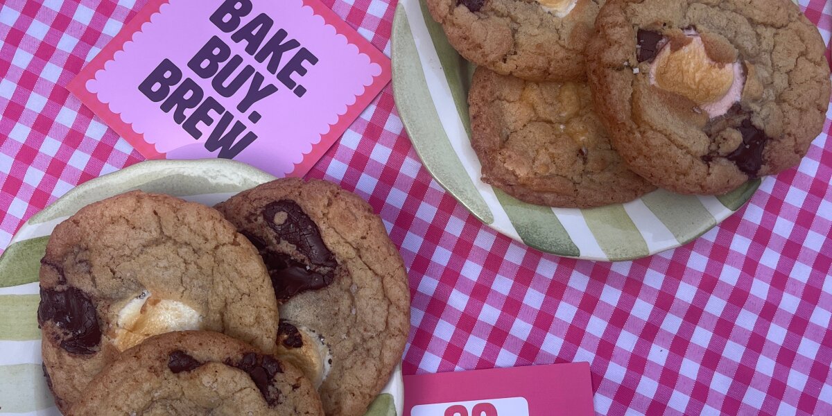 A photo of two plates of cookies on a pink and white tablecloth, alongside Breast Cancer Now Afternoon Tea fundraising materials
