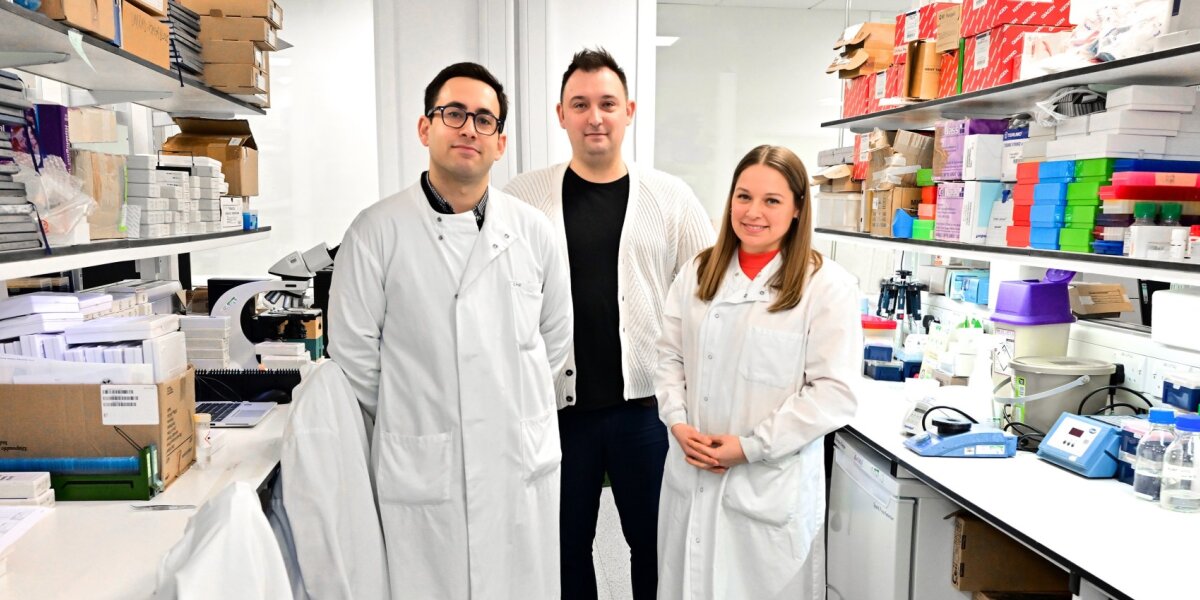 A photo of Arran Turnbull and 2 other researchers standing together in a lab.
