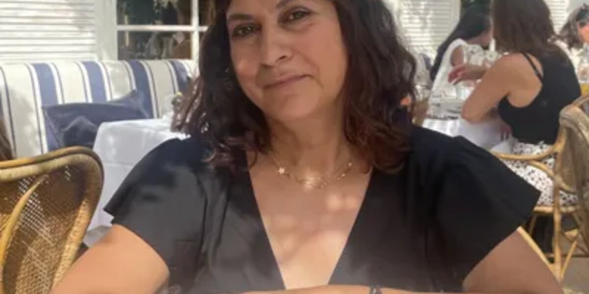 A photo of Evie's mum sitting at a table on a café terrace.
