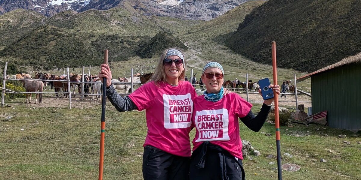 Emma and Jo wearing their pink Breast Cancer Now t-shirts with a snowy mountain in the background.
