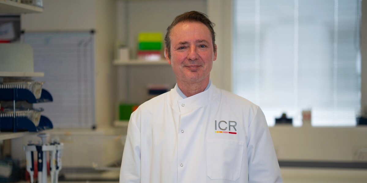 Researchers in white ICR lab coats in posing for photos in a lab.