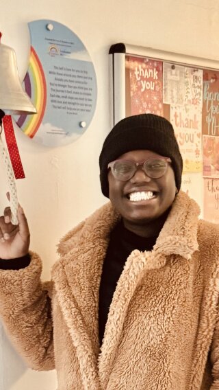 A photo of Abigail ringing a bell in a hospital to celebrate finishing treatment for breast cancer.