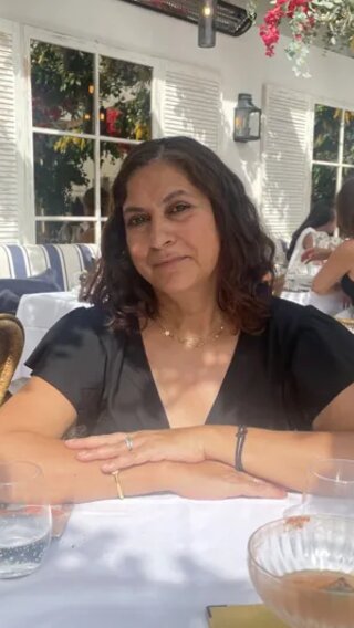 A photo of Evie's mum sitting at a table on a café terrace.