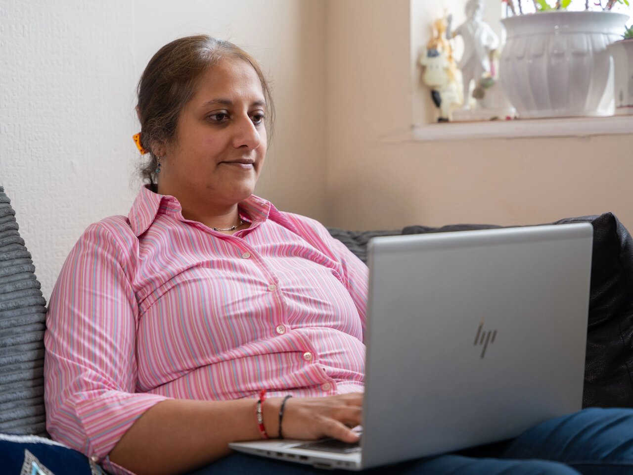 Anjli, a service pledge patient advocate volunteer , typing on her laptop.