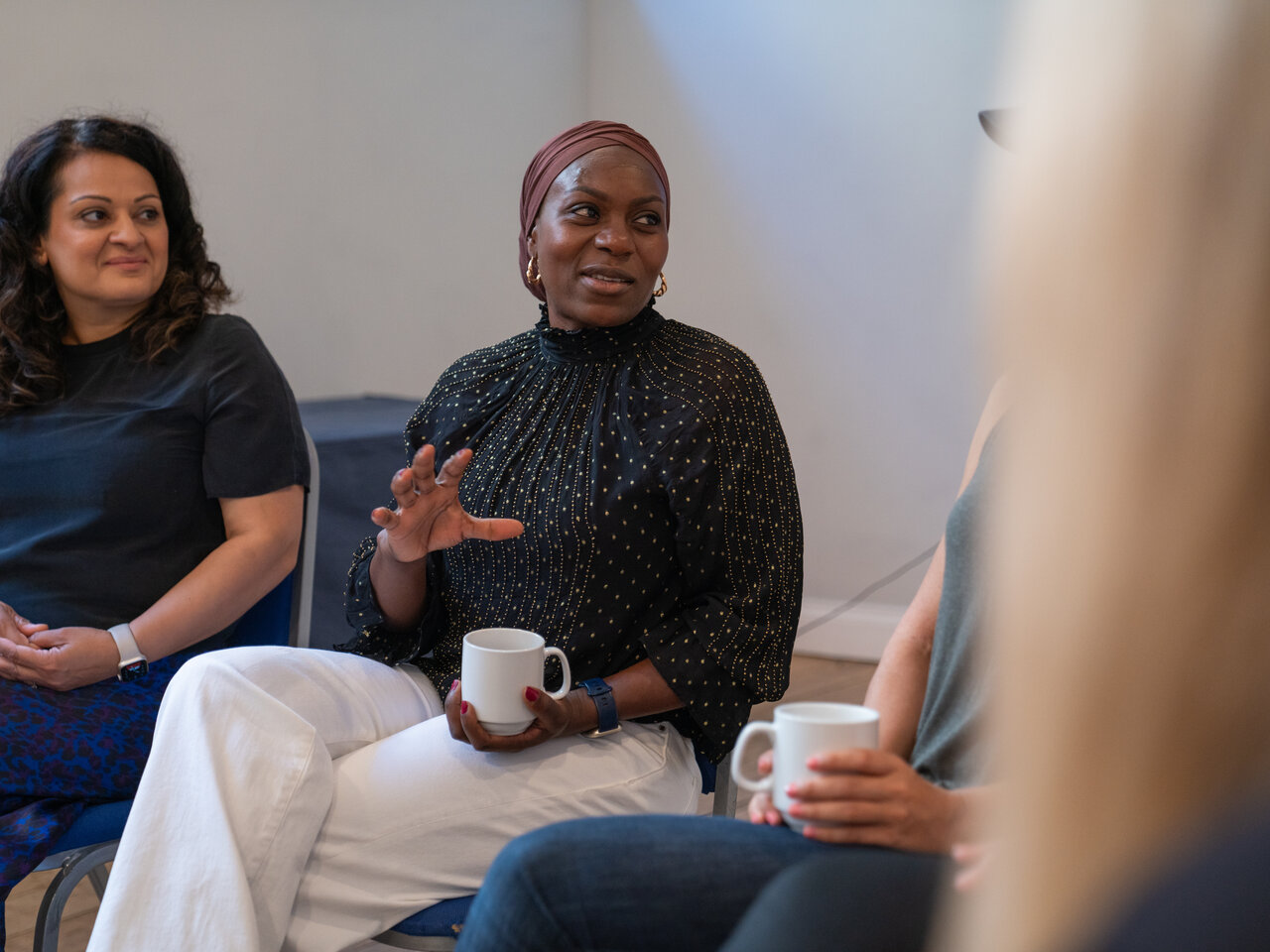 A group of women sat in a circle of chairs, in conversation with each other, during a Younger Women Together support service.