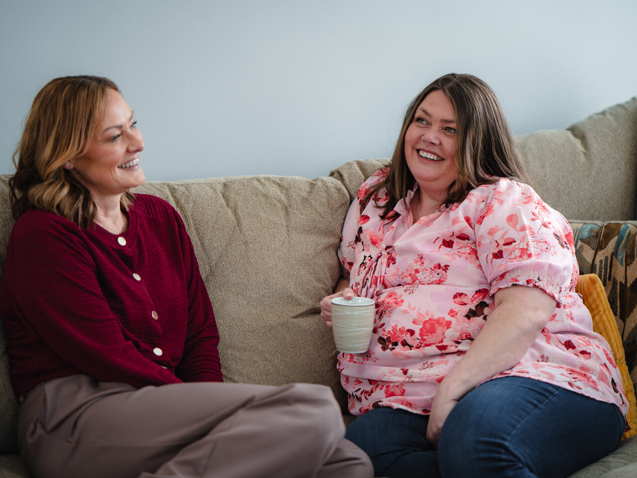 Emma and Joanne, chatting on their sofa in their home.