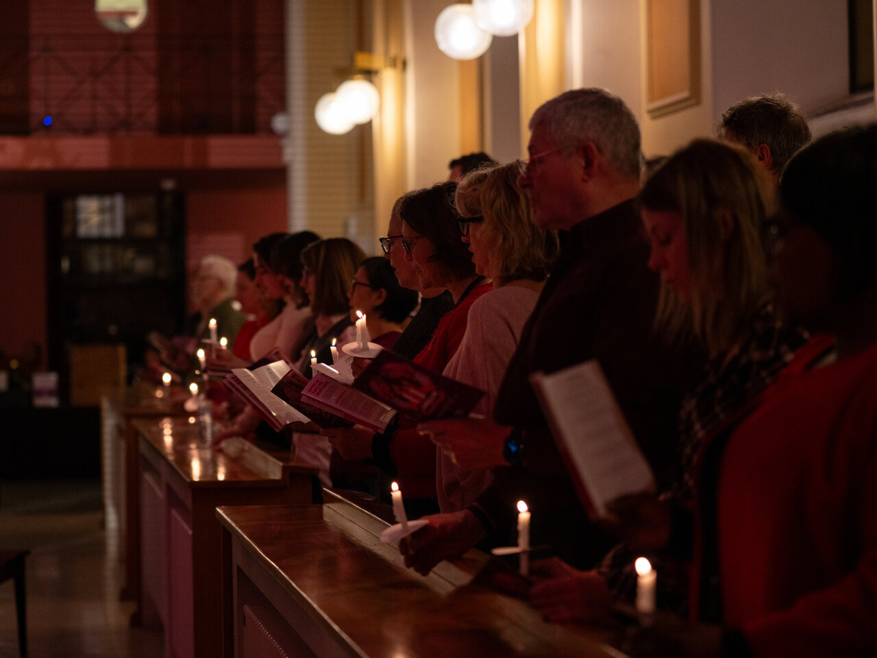 Photos of the carols concert, people singing, holding candles and enjoying the concert.