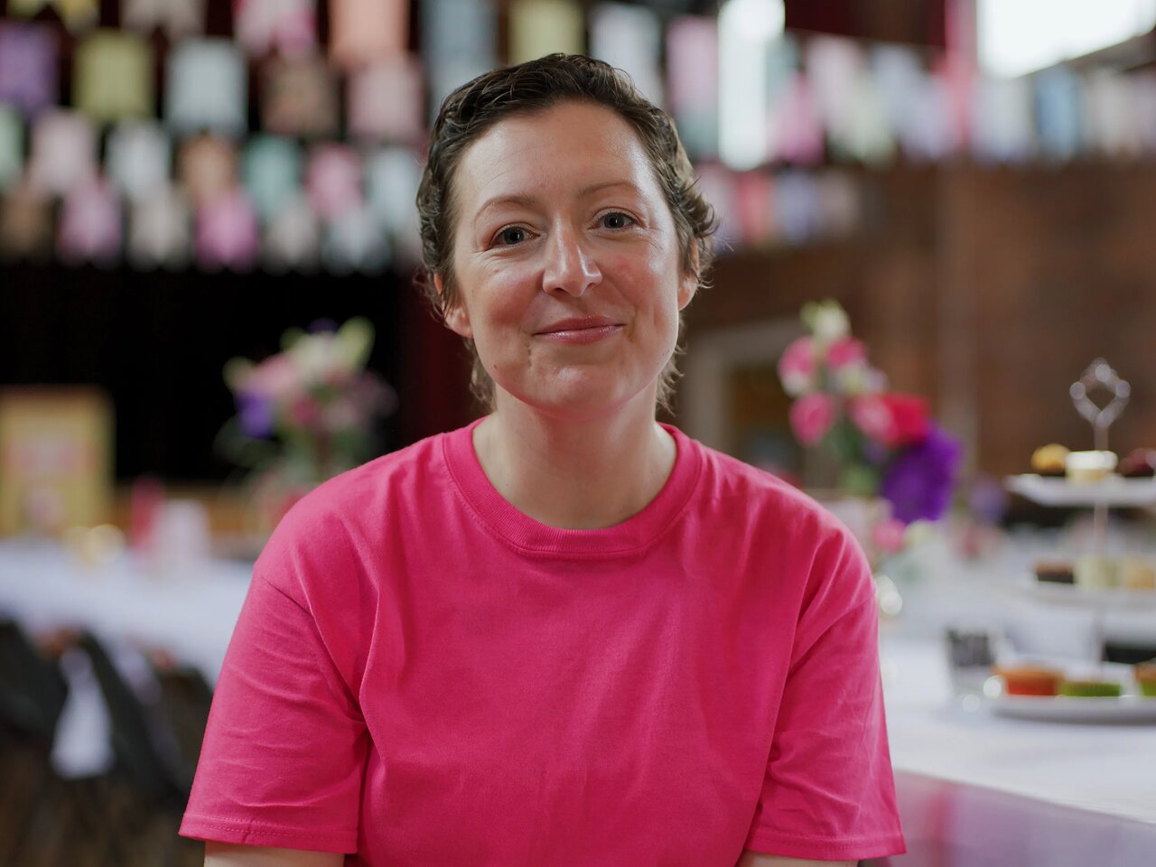 A photo of Amy wearing a pink t-shirt at an Afternoon Tea event.