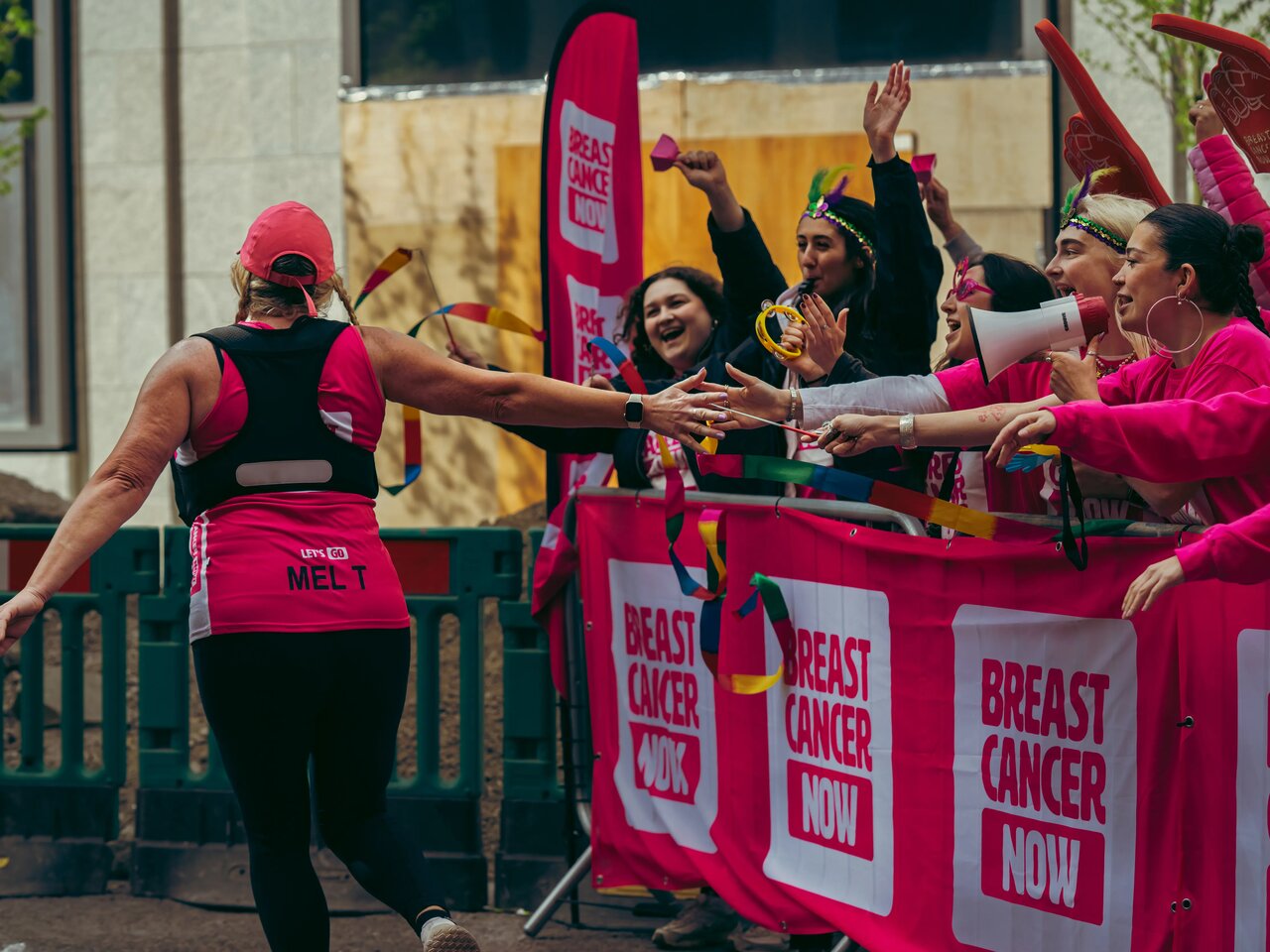 People wearing Breast Cancer Now pink running tops whilst running in the street at the London Landmarks half marathon.