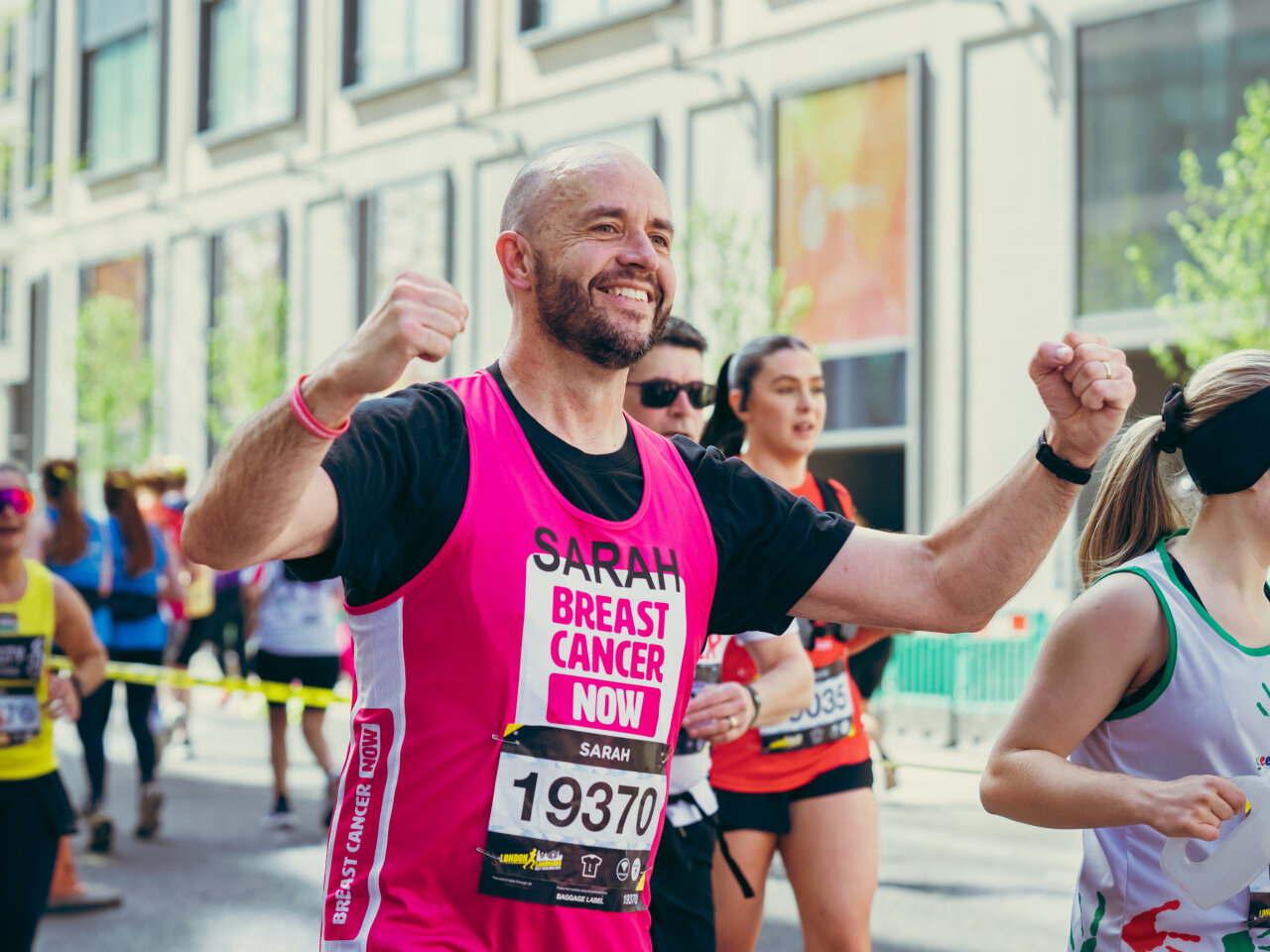 People wearing Breast Cancer Now pink running tops whilst running in the street at the London Landmarks half marathon.